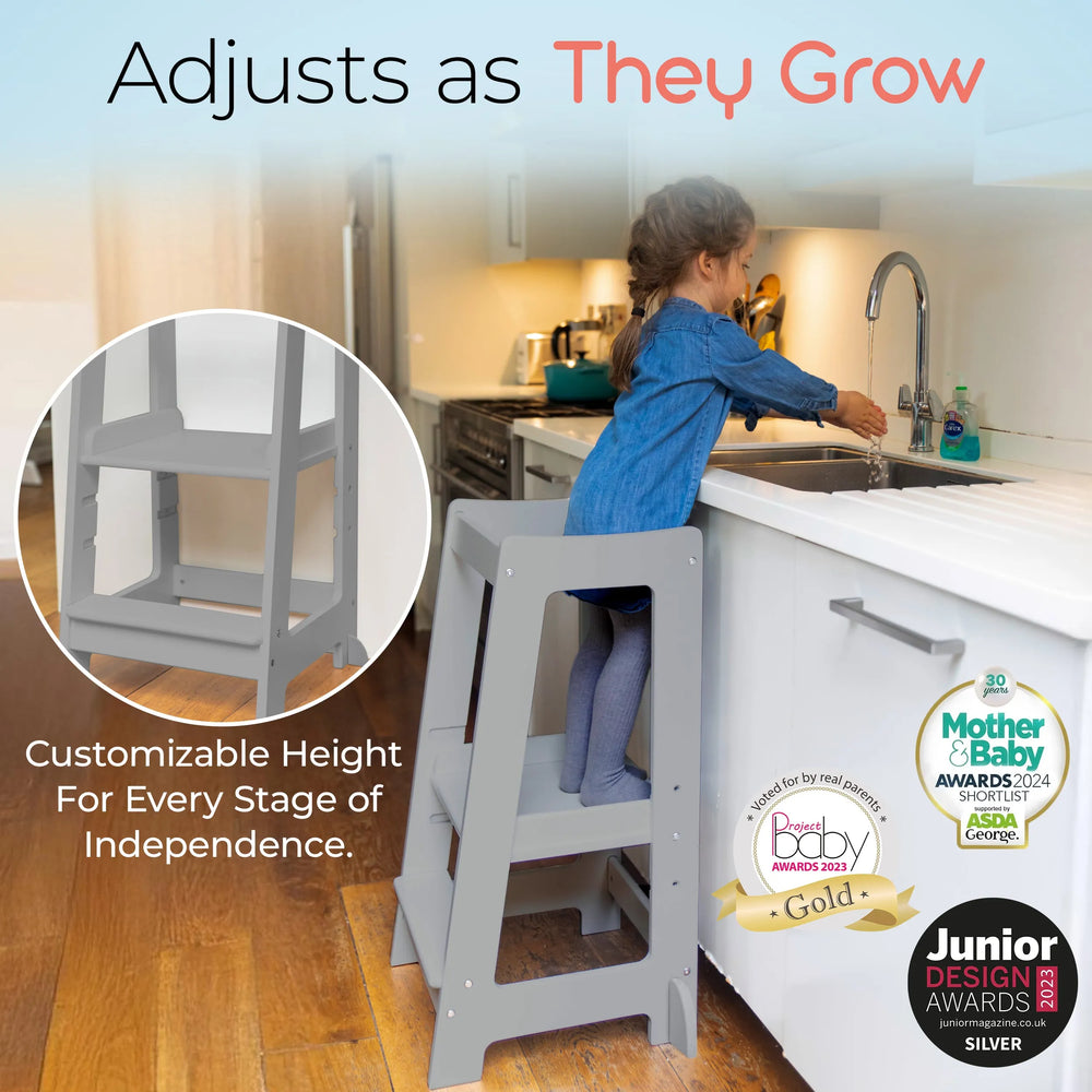 grey adjustable toddler tower positioned at kitchen sink for easy reach with awards