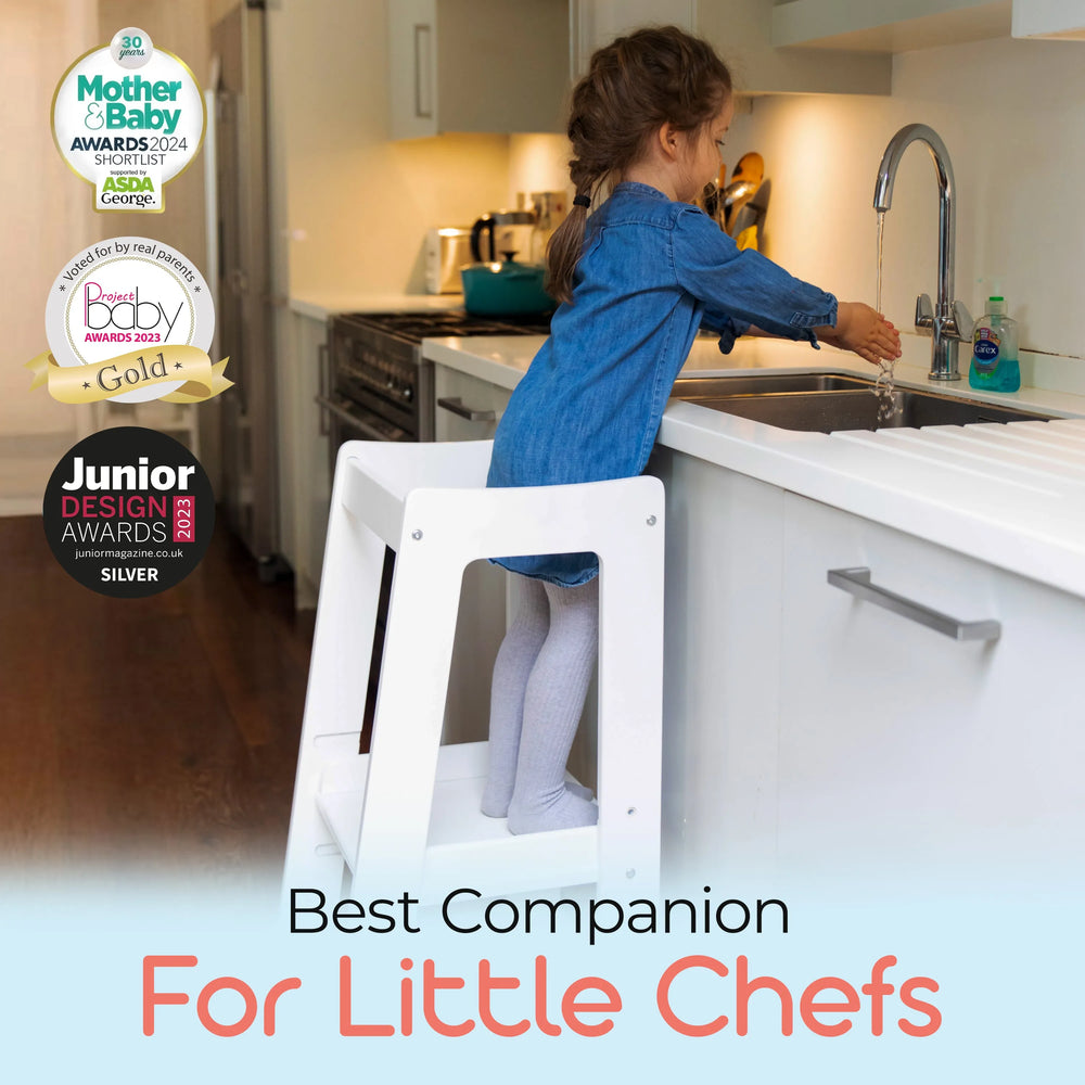 white adjustable toddler tower positioned at kitchen sink for easy reach with awards
